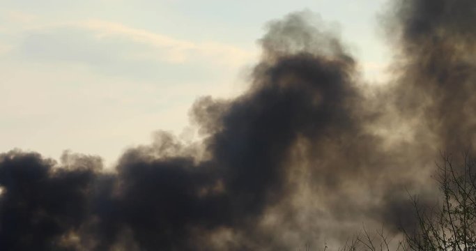 environmental destruction - dark grey smoke fills the sky as petrol leaks from a petroleum tank