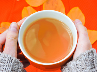 Cup of coffee, dry cracker cookies and dry leaves on an orange background. Autumn background, flat lay. Autumn composition. Autumn mood, top view. Cup of autumn coffee and yellow dry leaves.