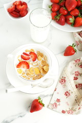 Healthy corn flakes with milk and strawberries for breakfast on marble background, desk, table.Top view. Copy space