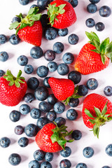 Strawberries and blueberries on pink background.