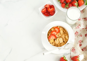 Healthy corn flakes with milk and strawberries for breakfast on marble background, desk, table.Top view. Copy space