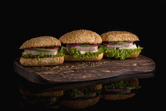  Sandwiches with ham, avocado, cheese and greens on a dark background