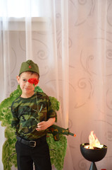 A boy in a military T-shirt and field cap with a carnation flower near the eternal flame. Victory...