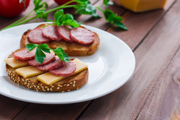 homemade open sandwich with rye bread sliced salami cheese and parsley on white plate wooden background