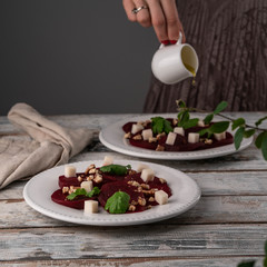beetroot salad with goats cheese and walnuts, olive oil dressing pouring down onto a salad