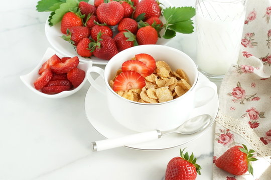 Healthy corn flakes with milk and strawberries for breakfast on marble background, desk, table.Top view. Copy space