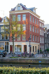 Amsterdam, Netherlands - April 09, 2019: Classic bicycles and historical houses in old Amsterdam. Typical street in Amsterdam with canal and colorful houses in the Dutch style on the Sunset.