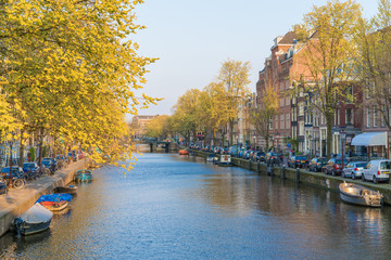 Amsterdam, Netherlands - April 09, 2019: Classic bicycles and historical houses in old Amsterdam. Typical street in Amsterdam with canal and colorful houses in the Dutch style on the Sunset.