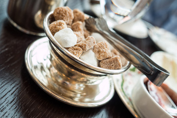 Brown and white sugar cubes and tongs in silver tea set