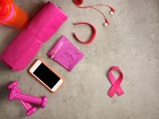 dumbbells, towel, smartphone and pink ribbon shaped elastic band