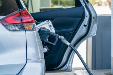 Car filling up gas tank at a gas station, with the door open