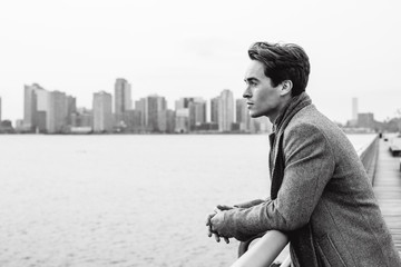 Handsome young man wearing winter clothes standing on the bridge in New York. Street photo concept.