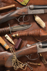 Hunting concept with shotgun, knife and ammunition for hunting arranged on brown background.