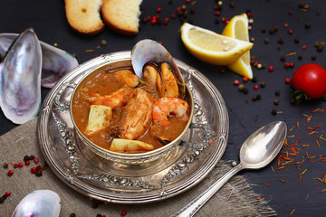French seafood soup. Bouillabaisse ear of seafood. Vintage silver plated plate and spoon. Black...
