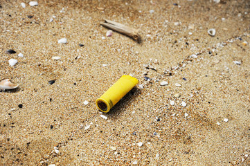 Hunting cartridge on the sand. Garbage on the beach. Dirty sea shore. Environmental pollution. Save...