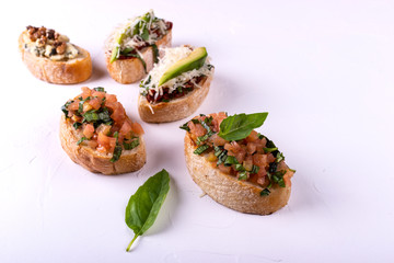 Set of assorted bruschetta with various toppings for holiday on white background. Top view. Party food concept.