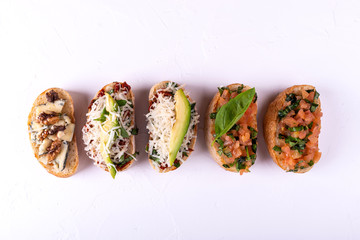 Set of assorted bruschetta with various toppings for holiday on white background. Top view. Party food concept.