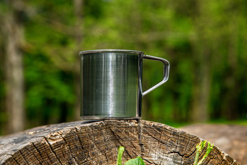 Obraz premium Tourist steel cup in the summer forest outdoors.