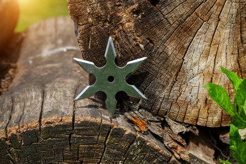 Shuriken (throwing star), traditional japanese ninja cold weapon stuck in wooden background