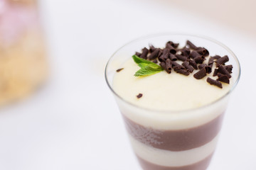 Layered chocolate pudding with yogurt decorated with chocolate crumb and in a glass at the bar counter. space for text. Closeup view.