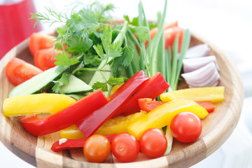 Organic farm. Fresh vegetables in wooden plate: yellow and red bell pepper, onion, tomato and cucumbers.