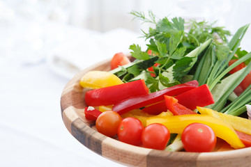 Organic farm. Fresh vegetables in wooden plate: yellow and red bell pepper, onion, tomato and cucumbers.