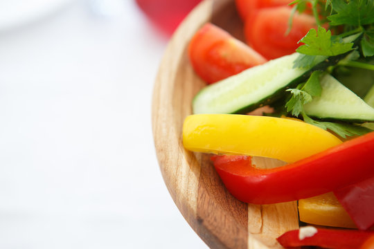 Organic farm. Fresh vegetables in wooden plate: yellow and red bell pepper, onion, tomato and cucumbers.