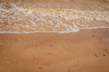 White waves of Azove sea on a red sand.