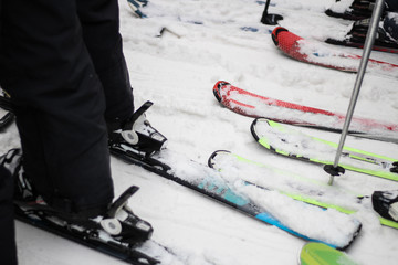 The queue for a ski lift from skis and snowboards. Colorful skis and snowboards