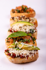 Variety of canape with hummus, tomato, avocado, cheese, walnut and fresh vegetables on white background. Top view of healthy snack concept.