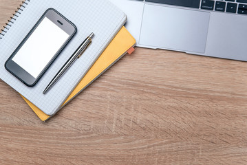 Flat lay of wooden office desk with laptop, smartphone, pen and notebook with copy space background.