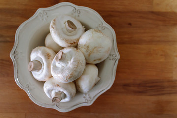 Top view of champignon mushrooms on rustic bowl
