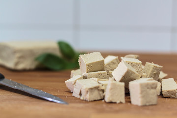 Tofu cubes and knife on wooden board