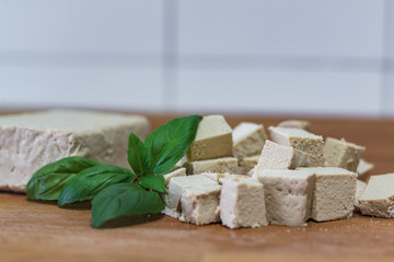 Tofu block and cubes of tofu on wooden cutting board
