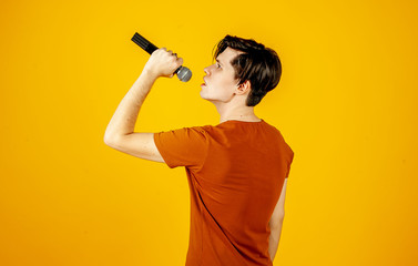 Karaoke man singing a song into a microphone, on a yellow background. A funny man holds a microphone in his hand at the karaoke singer singing a song! Pivets on a yellow background