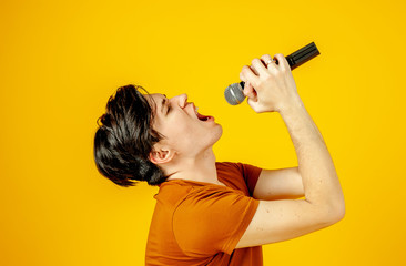 Karaoke man singing a song into a microphone, on a yellow background. A funny man holds a...