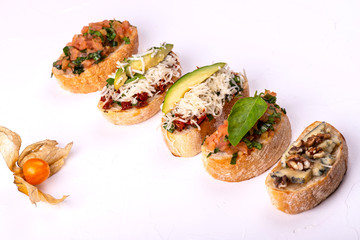 Variety of canape with hummus, tomato, avocado, cheese, walnut and fresh vegetables on white background. Top view of healthy snack concept.