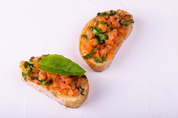 Tasty savory tomato Italian appetizers, or bruschetta, on slices of toasted baguette garnished with basil.