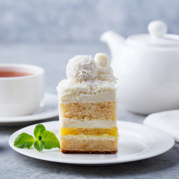 Coconut layered, raffaello cake on white plate. Grey background. Close up.