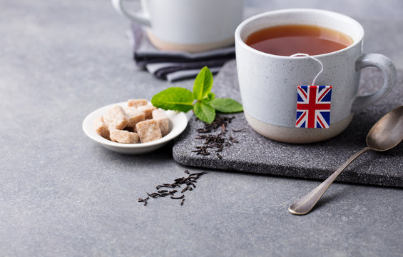 Tea in mugs with British flag tea bag label. Grey background. Copy space.