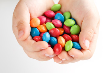 Multicolored candies in the hands of a child on a white isolated background