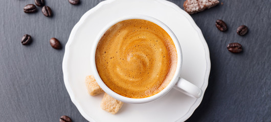 Coffee espresso in white cup on black slate background. Top view.