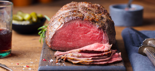 Roast beef on cutting board. Wooden background. Close up. - obrazy, fototapety, plakaty