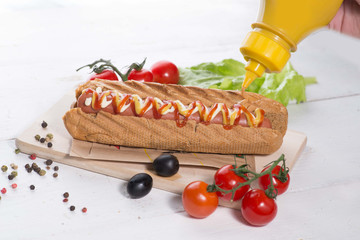 hot dog poured mustard out of the jar. Served table with vegetables and spices