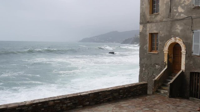 view of a courtyard of Erbalunga with the rough sea. An ancient fishing village in Corsica, Cap Corse, Corsica, France, Europe