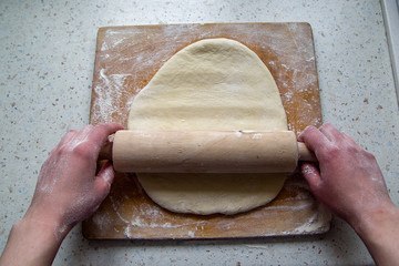 Woman's hands roll the dough. First-person view