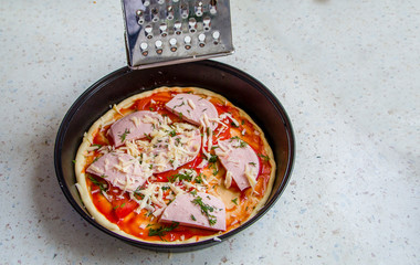 grater sprinkles the pizza with cheese