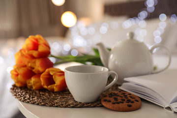 Composition with cup of tea and flowers on table against blurred background. Space for text