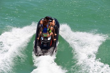 Overhead view of a young couple riding tandem on a black jet ski