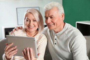 Mature couple using video chat on tablet at home